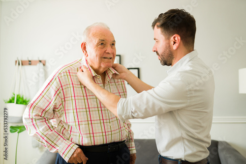 Smiling old man getting dressed to go out with his son