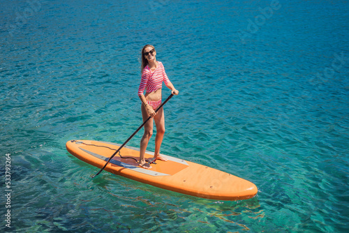 Young women Having Fun Stand Up Paddling in blue water sea in Montenegro. SUP. girl Training on Paddle Board near the rocks Portrait of a disgruntled girl sitting at a cafe table © galitskaya