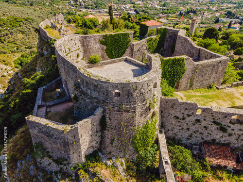 Old city. Sunny view of ruins of citadel in Stari Bar town near Bar city, Montenegro. Drone view Portrait of a disgruntled girl sitting at a cafe table