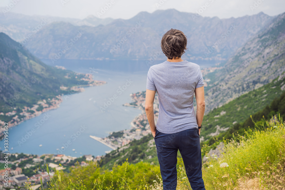 Man tourist enjoys the view of Kotor. Montenegro. Bay of Kotor, Gulf of Kotor, Boka Kotorska and walled old city. Travel to Montenegro concept. Fortifications of Kotor is on UNESCO World Heritage Man tourist enjoys the view of Kotor. Montenegro. Bay of Kotor, Gulf of Kotor, Boka Kotorska and walled old city. Travel to Montenegro concept. Fortifications of Kotor is on UNESCO World Heritage