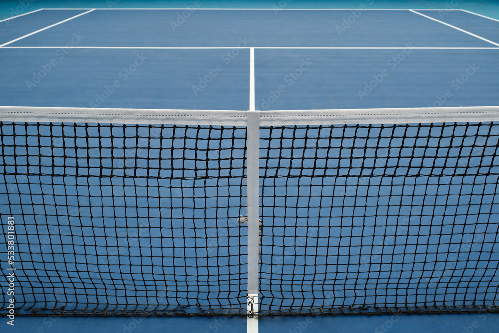 Horizontal high angle no people conceptual shot of modern tennis court with blue floor and net, copy space Horizontal high angle no people conceptual shot of modern tennis court with blue floor and net, copy space