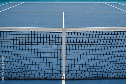 Horizontal high angle no people conceptual shot of modern tennis court with blue floor and net, copy space photo