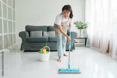 Young woman cleaning floor using mop at home.