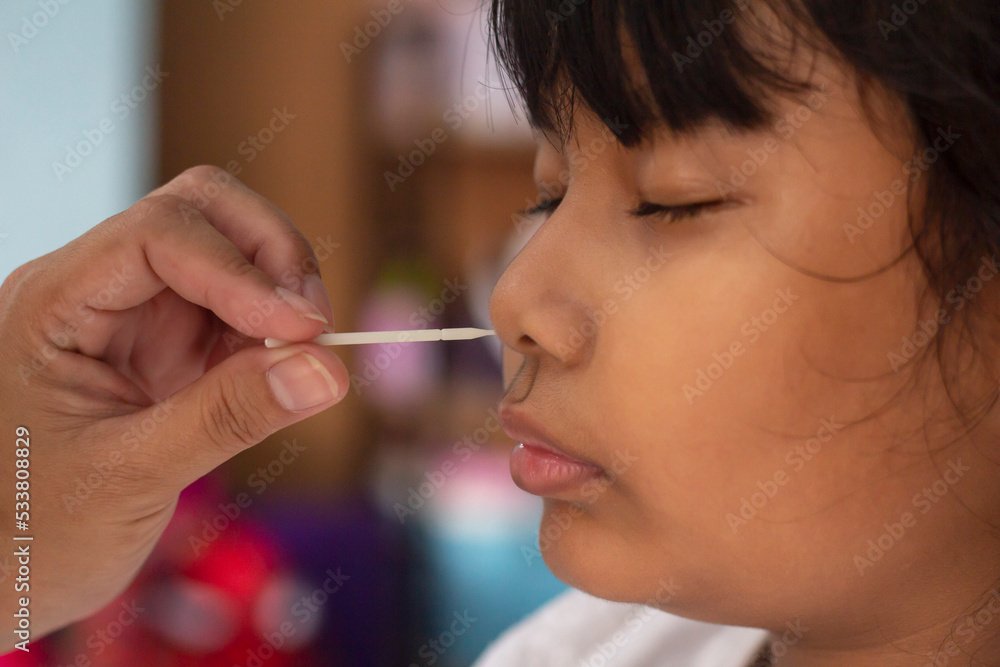 Asian girl getting nasal swab rapid self-testing antigen kits (atk) Coronavirus disease (Covid-19) test for children at home. Asian girl getting nasal swab rapid self-testing antigen kits (atk) Coronavirus disease (Covid-19) test for children at home.