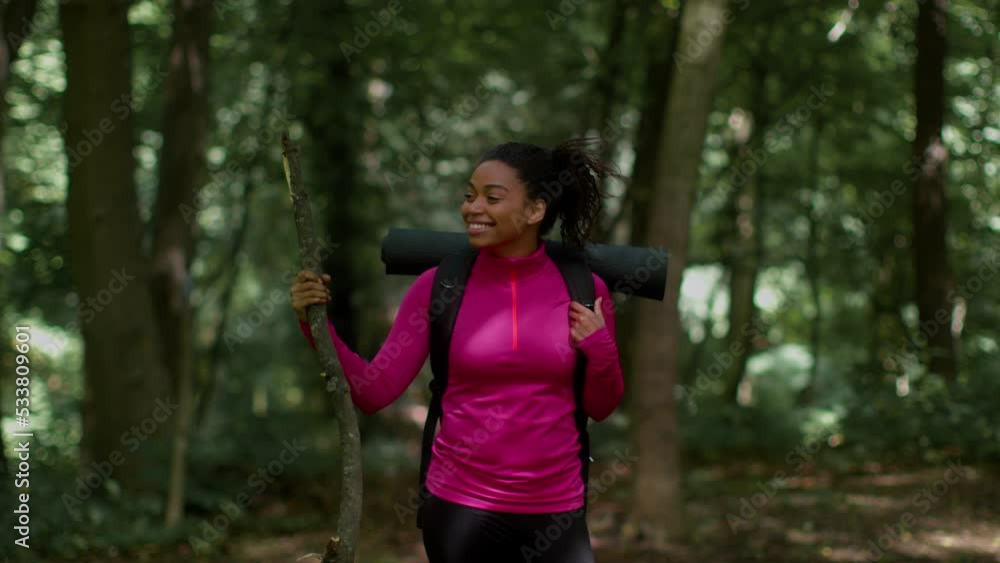 Happy young african american woman explorer with backpack standing in forest, enjoying nature around, slow motion Happy young african american woman explorer with backpack standing in forest, enjoying nature around, slow motion
