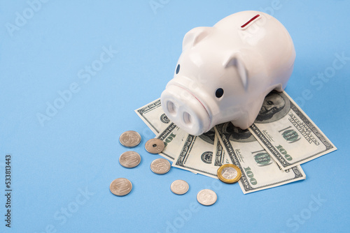 piggy bank save money with banknote and coin from top view, blue desk background, copy space on Left side