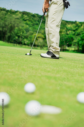 golfer practice putting a golf ball into a training hole on the green, golf course on summer time