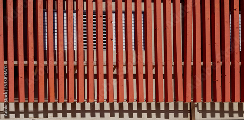 Red Wooden Facade in Front of a Tan Building.