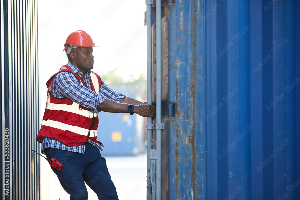 African factory worker or foreman opening the container door in warehouse storage African factory worker or foreman opening the container door in warehouse storage