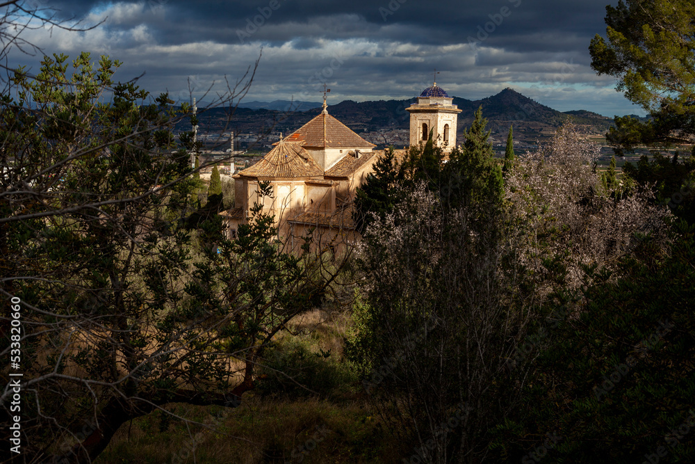 Fototapeta premium sun rays hitting old town chapel in the forest with cloudy sky background