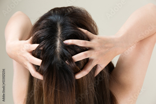 女性は頭皮のマッサージをしている。