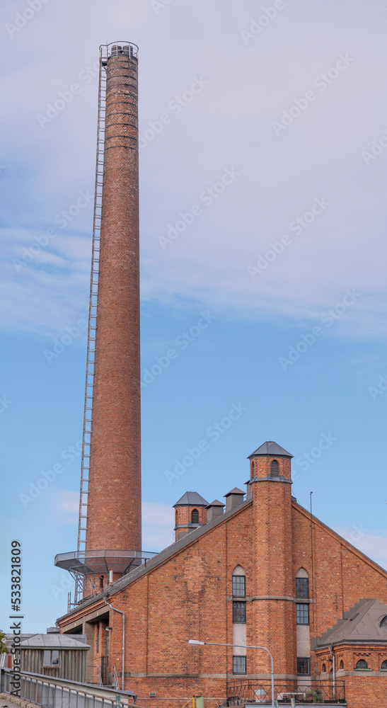 Tall red brick chimney and ventilations towers on a brick factory building an autumn afternoon day in Stockholm