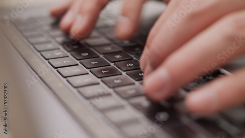 Close up macro of hands typing on laptop keyboard mac computer