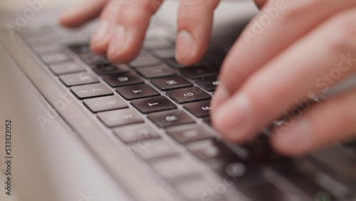 Close up macro of hands typing on laptop keyboard mac computer