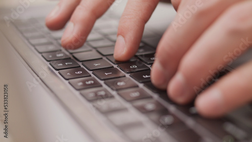 Close up macro of hands typing on laptop keyboard mac computer