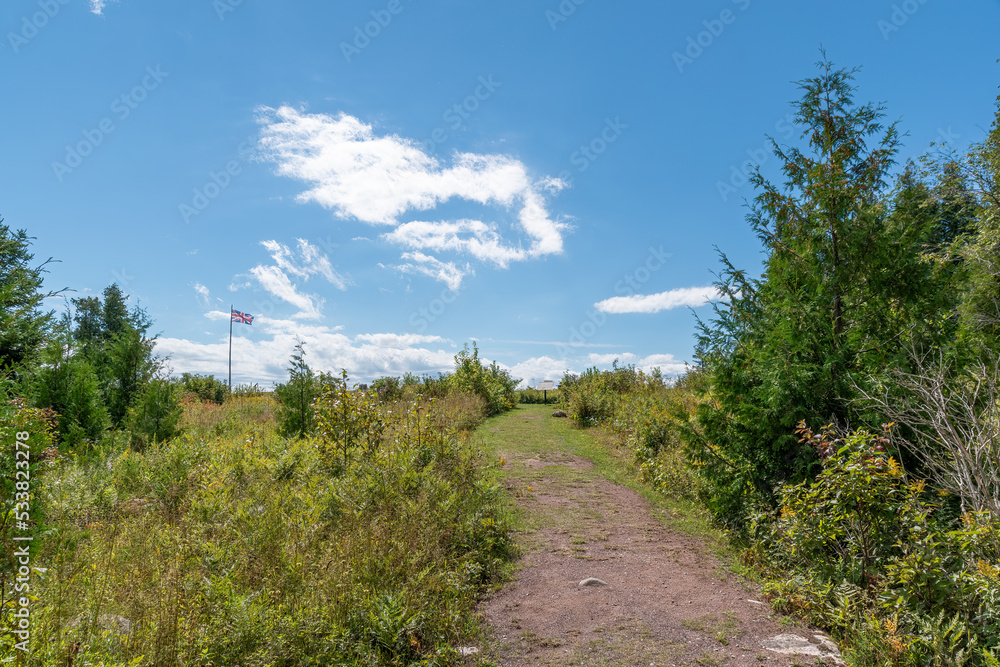 Obraz premium A dirt path leads through a clearing in a forest, leading towards the ruins of Fort St. Joseph from the War of 1812.