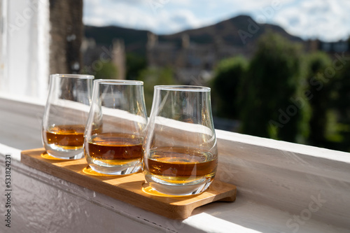 Flight of single malt scotch whisky served on old window sill in Scottisch house with view on old part of Edinburgh, Scotland, UK © barmalini