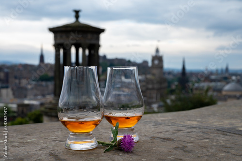 Two glasses of single malt scotch whisky and view from Calton hill to park and old parts of Edinburgh city in rainy day, Scotland, UK