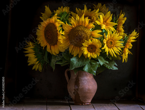 Fotografie beautiful yellow Sunflower still life bouquet  in a clay jug ceramic rustic style oil honey Dark photo background wooden table Vintage