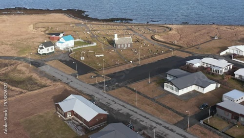 Flying towards small church with graveyard on Atlantic coastline of Iceland, aerial photo