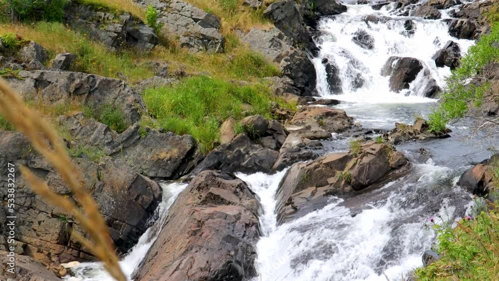 Water gently cascades down a rocky incline in a small river. Water gently cascades down a rocky incline in a small river.