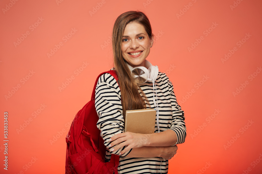 Smiling university student in striped shirt with book and red backpack isolated woman portrait on pink background. Smiling university student in striped shirt with book and red backpack isolated woman portrait on pink background.