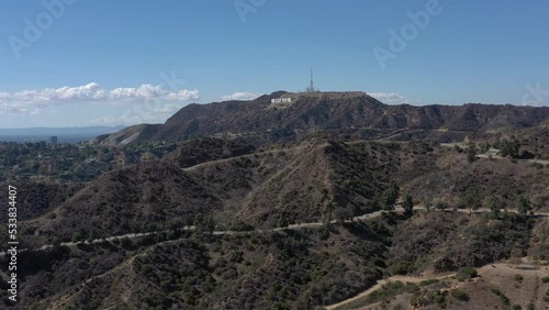 Aerial bird's eye view flying above Griffith Park hills towards the iconic Hollywood sign.