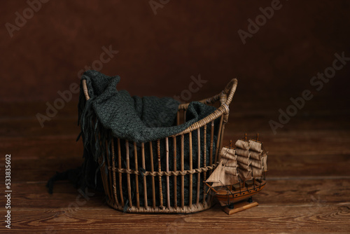 Newborn photography digital background prop. Vintage basket with a toy sailboat on a wooden background.