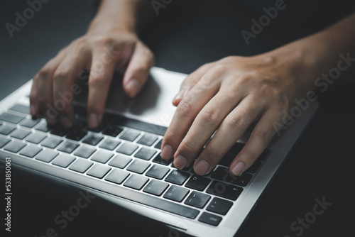 Man using computer laptop working internet searching social media and communications digital technology online at desk.