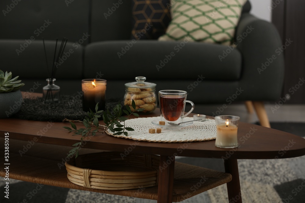 Tea, cookies and decorative elements on wooden table in living room