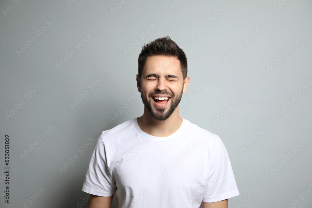 Obraz premium Young man laughing on light grey background. Funny joke