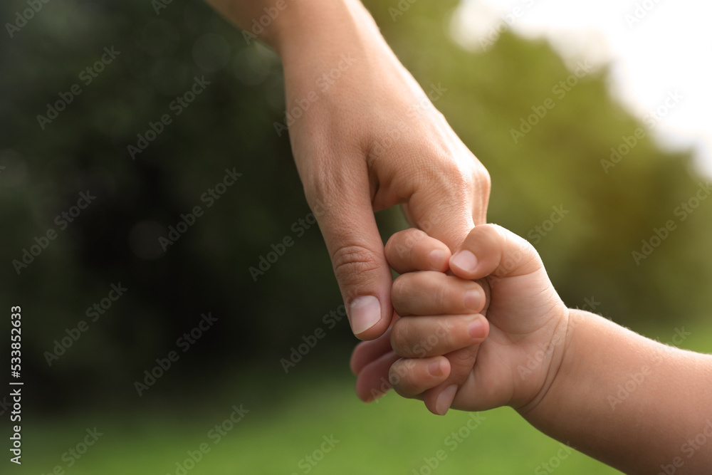 Daughter holding mother's hand in park, closeup. Happy family Daughter holding mother's hand in park, closeup. Happy family
