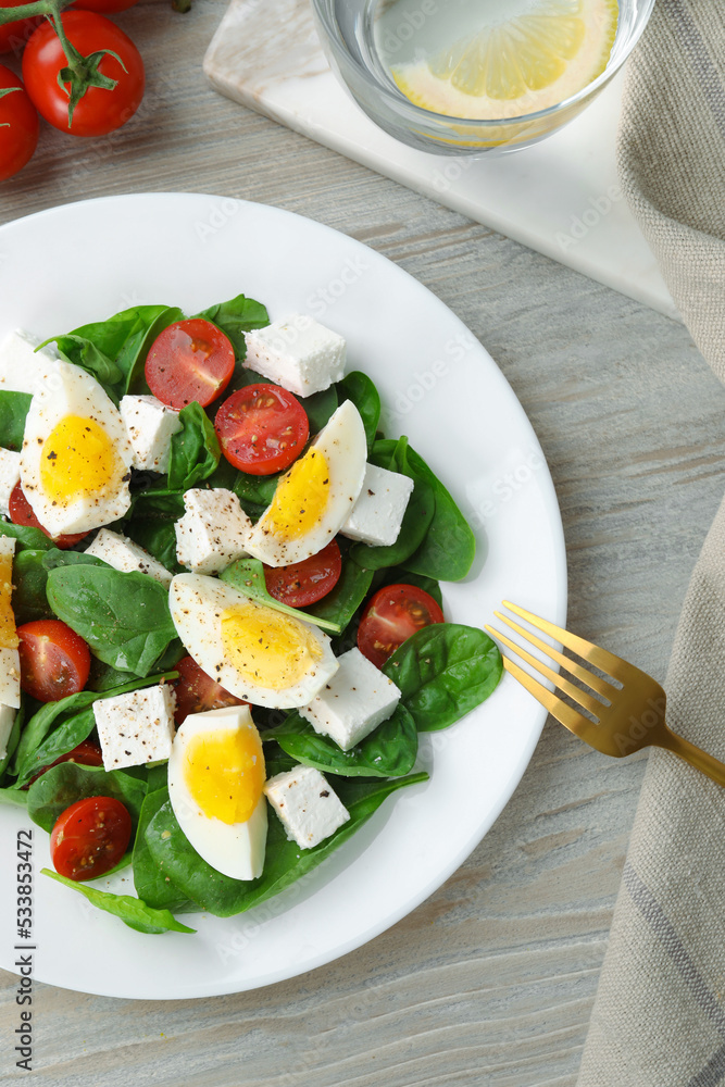 Delicious salad with boiled eggs, feta cheese and tomatoes served on wooden table, flat lay