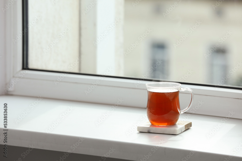 Cup of hot tea on white sill near window. Space for text Cup of hot tea on white sill near window. Space for text