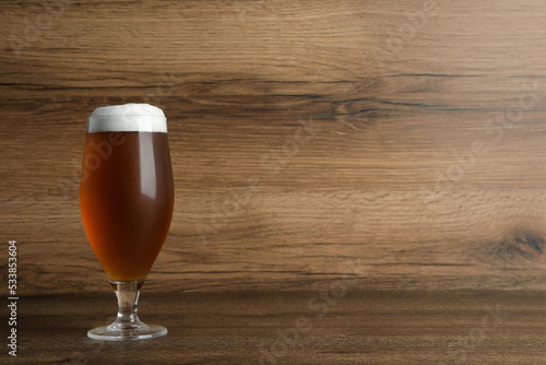 Glass of tasty beer on wooden table. Space for text