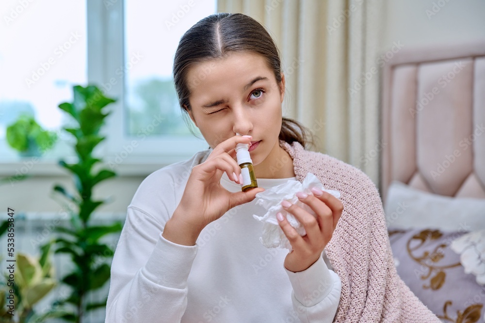 Teenage girl with runny nose treating rhinitis using nose drops spray Teenage girl with runny nose treating rhinitis using nose drops spray