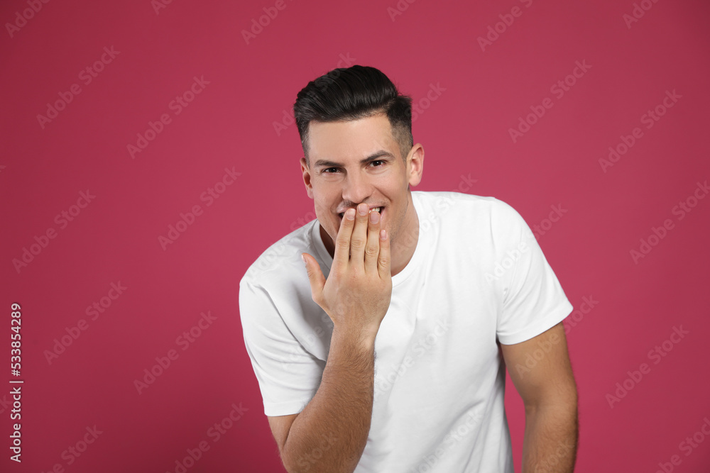 Handsome man laughing on maroon background. Funny joke Handsome man laughing on maroon background. Funny joke