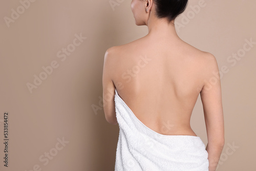 Back view of woman with perfect smooth skin on beige background, space for text photo