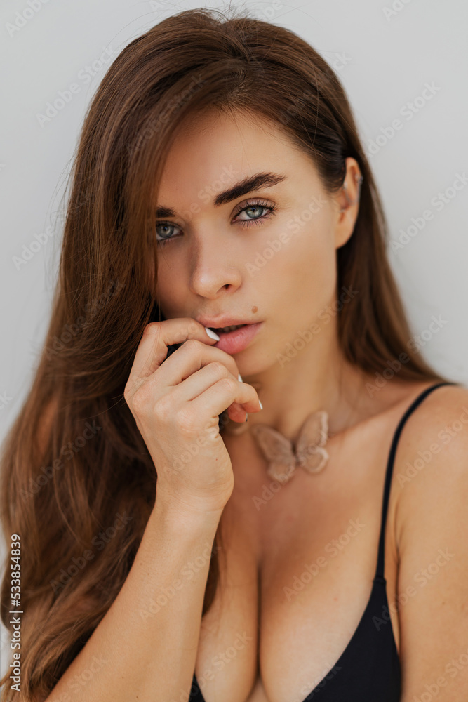 Close up portrait of seductive bunette woman posing over white wall. Healthy long hairs. Fashionable necklase. Close up portrait of seductive bunette woman posing over white wall. Healthy long hairs. Fashionable necklase.