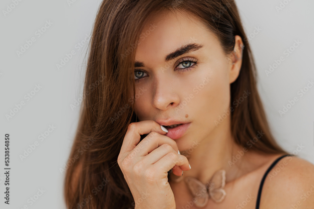 Close up portrait of seductive bunette woman posing over white wall. Healthy long hairs. Fashionable necklase. Close up portrait of seductive bunette woman posing over white wall. Healthy long hairs. Fashionable necklase.