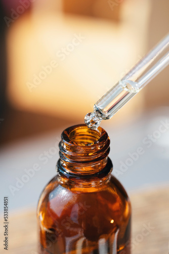 Open amber bottle with dropper pipette with serum or essential oil and shadows. Skincare products, natural cosmetic on blurred background.