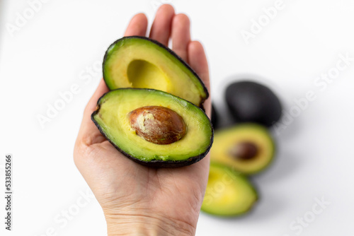 Avocado held in hand. White background.
