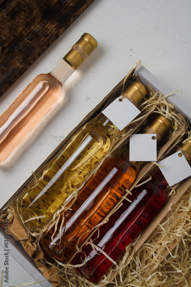 Naklejka premium Assortment of 250 ml bottles of red, pink, white wine in box of wooden shavings, no label. Set of alcohol drinks for present or celebration