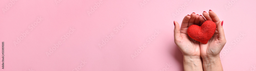 A large horizontal banner with women's hands holding a knitted red heart. Love, mercy, donation A large horizontal banner with women's hands holding a knitted red heart. Love, mercy, donation
