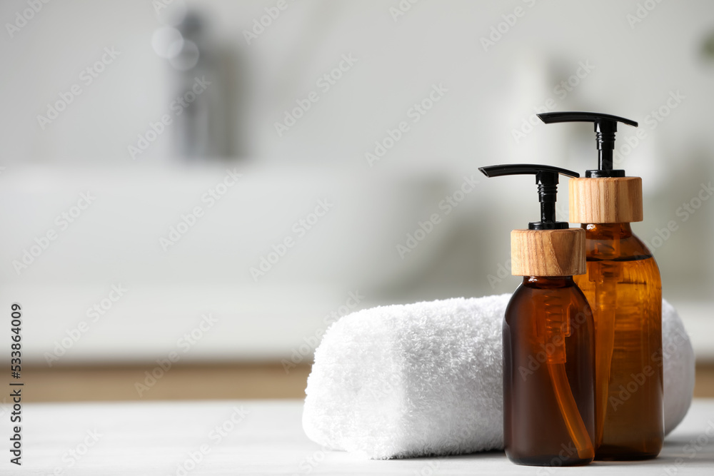 Personal care products and rolled towel on white wooden table in bathroom, closeup. Space for text Personal care products and rolled towel on white wooden table in bathroom, closeup. Space for text