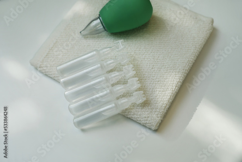 Single dose ampoules of sterile isotonic sea water solution, towel and nasal aspirator on white table photo