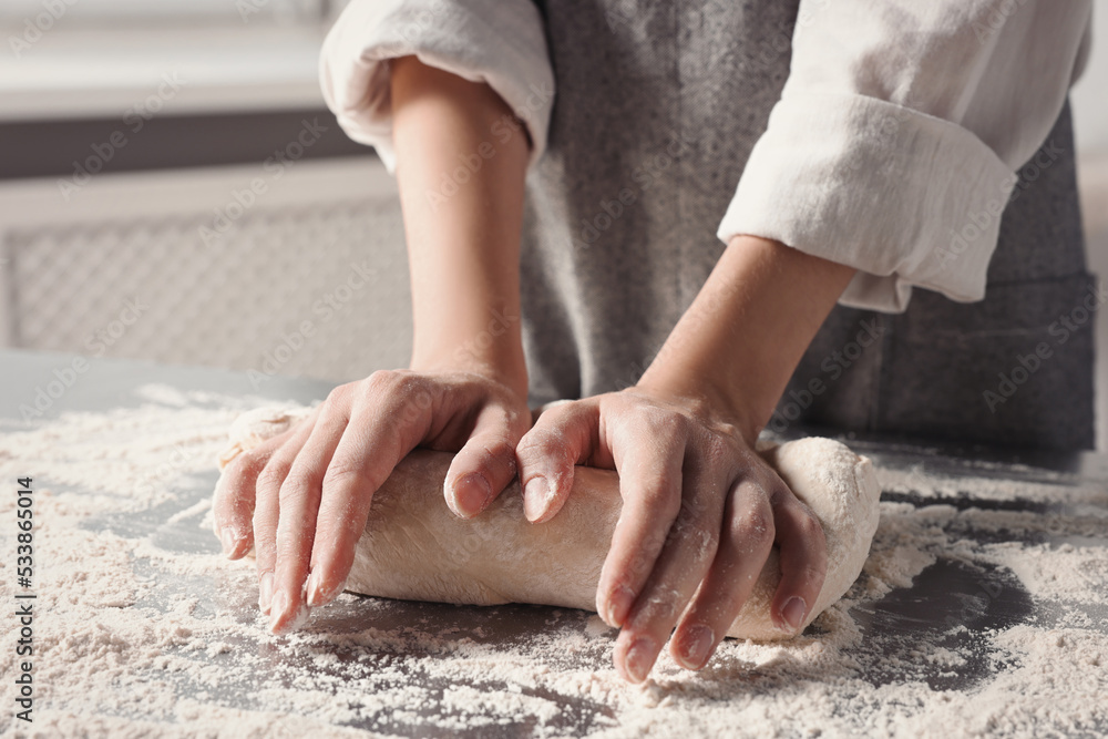 Woman kneading dough at table in kitchen, closeup Woman kneading dough at table in kitchen, closeup