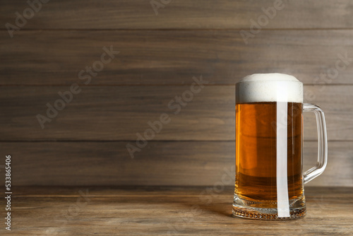 Mug of tasty beer on wooden table. Space for text