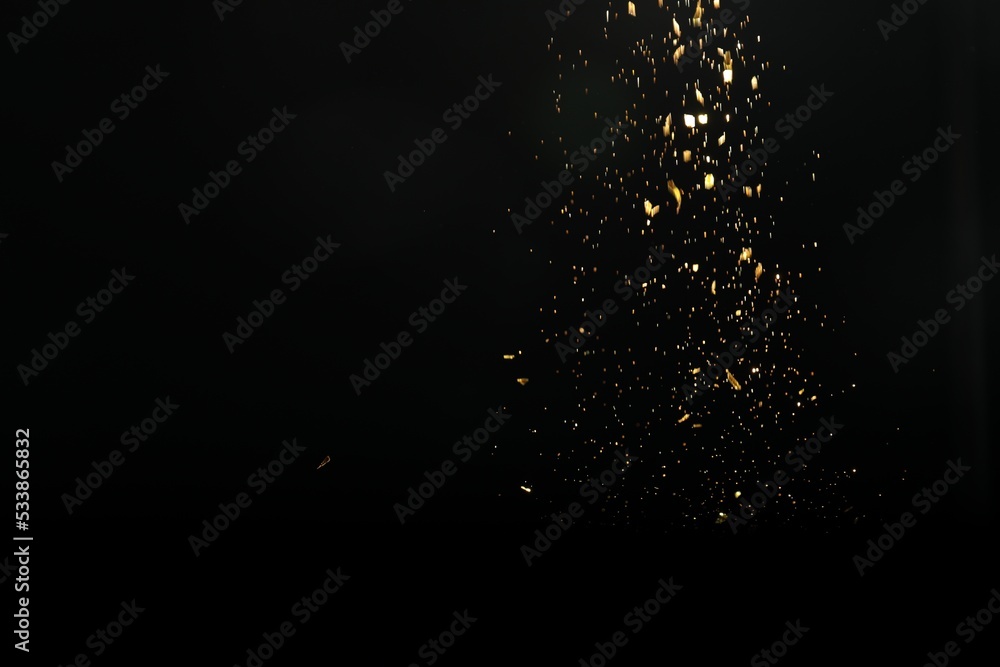 Fototapeta premium Shiny golden glitter falling down on black background. Bokeh effect