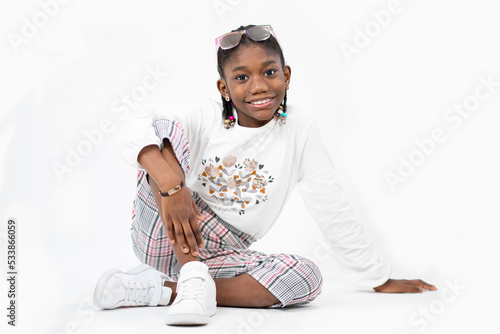 giovane ragazza sorridente seduta sul pavimento in studio bianco e isolare photo